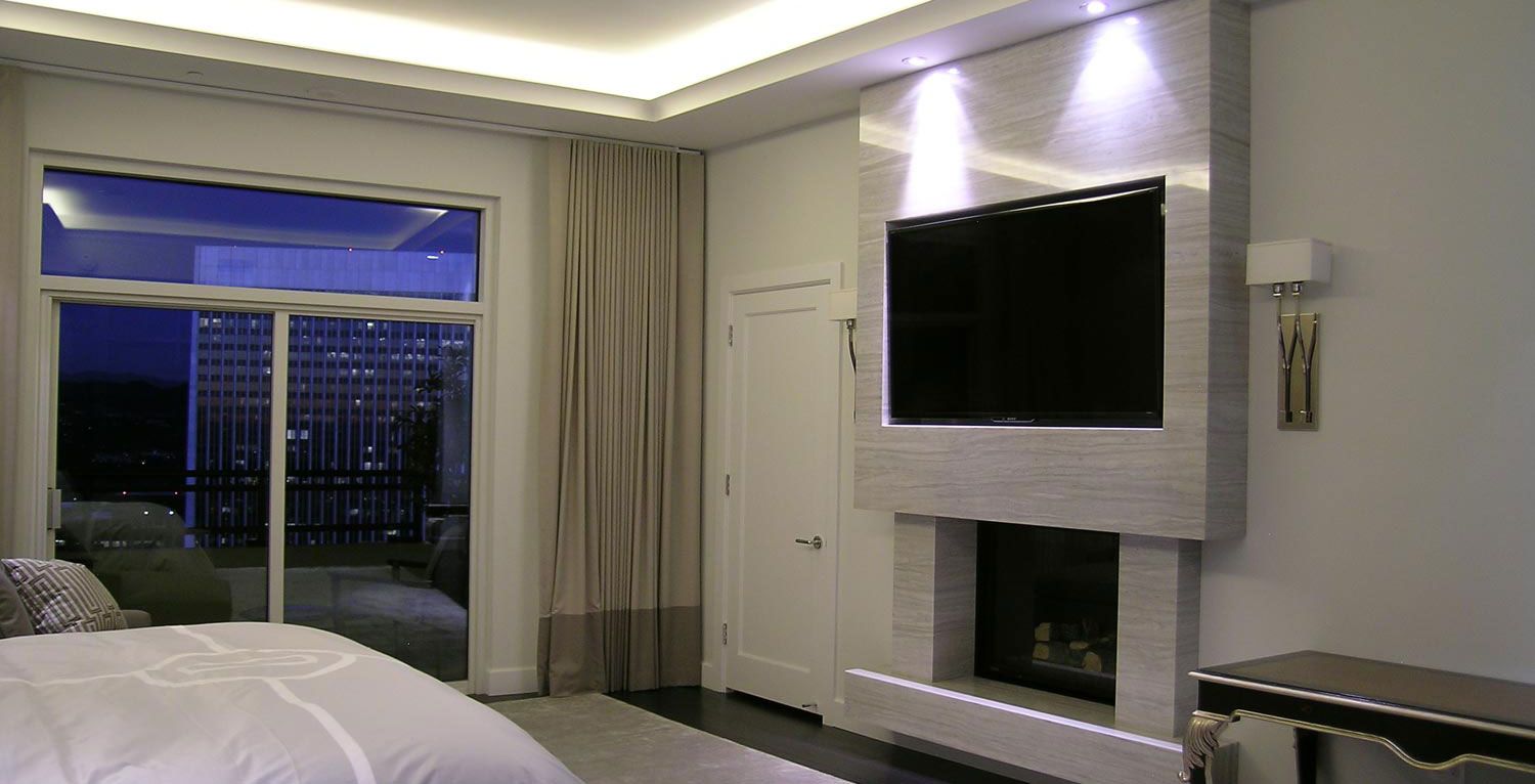 Bedroom of a smart home with lights, blinds, tv, and a fireplace.