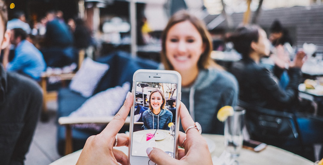 Woman posing for a photo being taken on a phone.