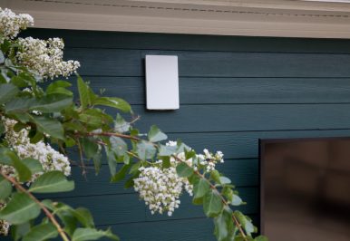 A home networking device mounted to the outside of a house.